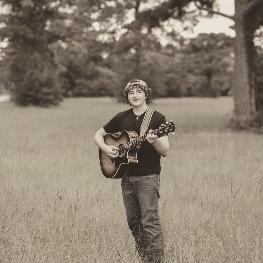 Ben Hogan playing acoustic guitar in a grassy field